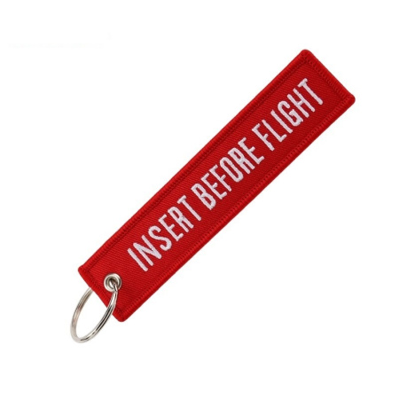 Keychain Insert Before Flight in red with white text